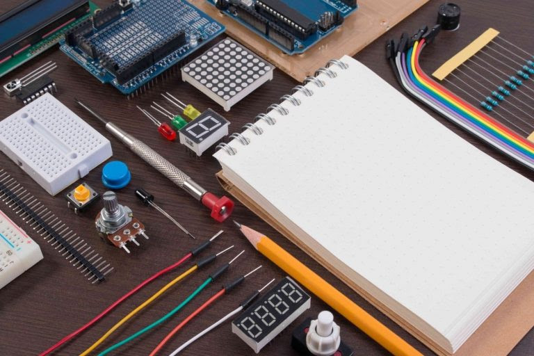 edusurvey various electronic parts, pencils, a pad of paper are all neatly arranged on a table