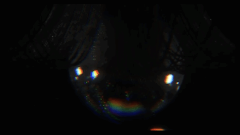 Nearly black background with a glossy eye protruding from the darkness in shadow