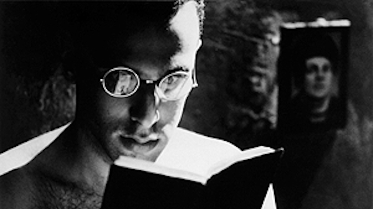 Black and white still of a man reading a book